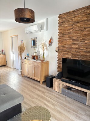 A modern living room with a wooden cabinet, a television, and a hanging light fixture.