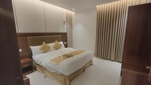 A hotel room with a large bed, a nightstand, a wooden headboard, and a curtain on the window.