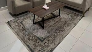 A modern living room with a sofa, armchairs, a coffee table, and a patterned rug.