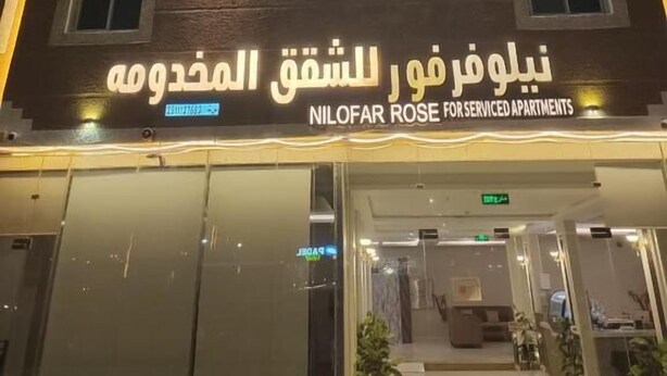 A building with a sign for 'NiloFar Rose For Serviced Apartments' in Arabic and English.