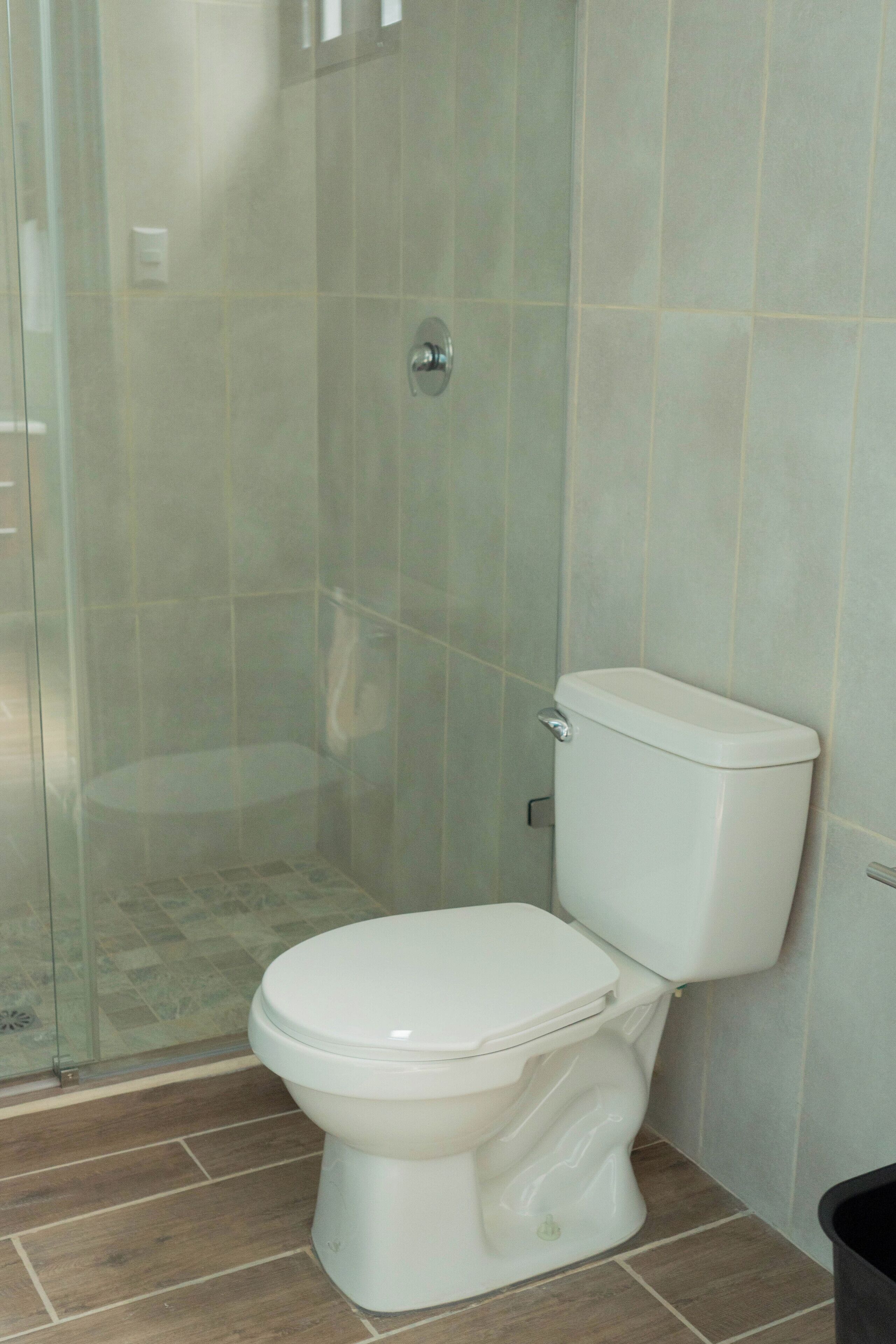 A bathroom with a glass shower enclosure, a white toilet, and tiled walls.