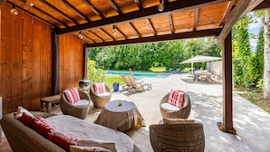 Un patio al aire libre con mobiliario de mimbre, piscina y techo de madera.