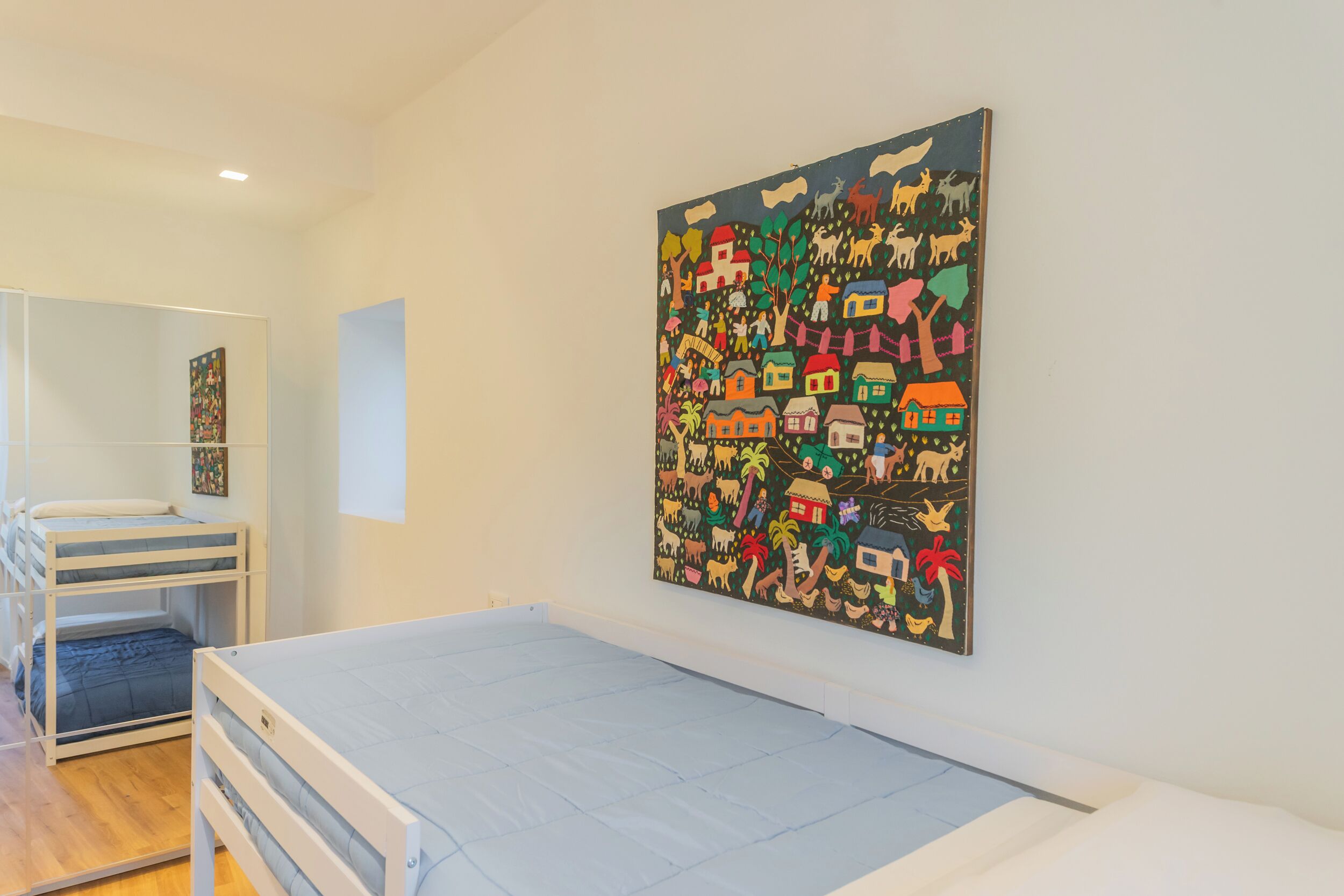 Une chambre avec des lits superposés, une grande fresque murale et une fenêtre.