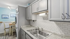 A kitchen with white cabinets, a double sink, and a tiled backsplash.