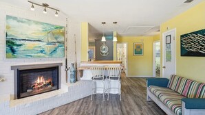 A living room with a fireplace, a dining area with a bar, and a sofa.