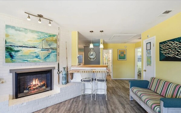 A living room with a fireplace, a dining area with a bar, and a sofa.