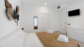 Une chambre d’hôtel équipée d’un lit, d’un téléviseur à écran plat, d’un miroir et d’une commode.
