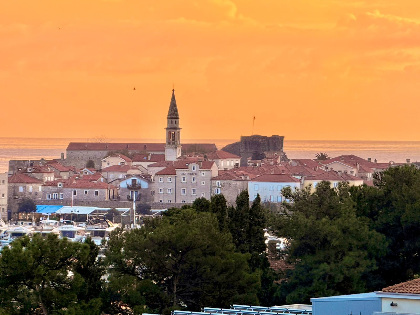 A coastal town with historic buildings, a prominent tower, and a fortified structure.