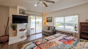 A bedroom with a bed, a ceiling fan, a TV, a sliding glass door to a balcony, and a window with blinds. - Conch Nation – 4 Bedroom / 3 Bath Gulfside Home with Dockage (Marathon)