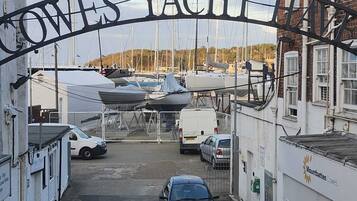 Der Eingang einer Marina mit einem Schild, auf dem 'OWES YACHTS' steht, und einem parkenden Auto im Vordergrund.