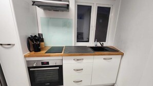 Una cucina compatta con forno Bosch, lavastoviglie integrata, una finestra con vetro smerigliato e una cappa in acciaio inossidabile.