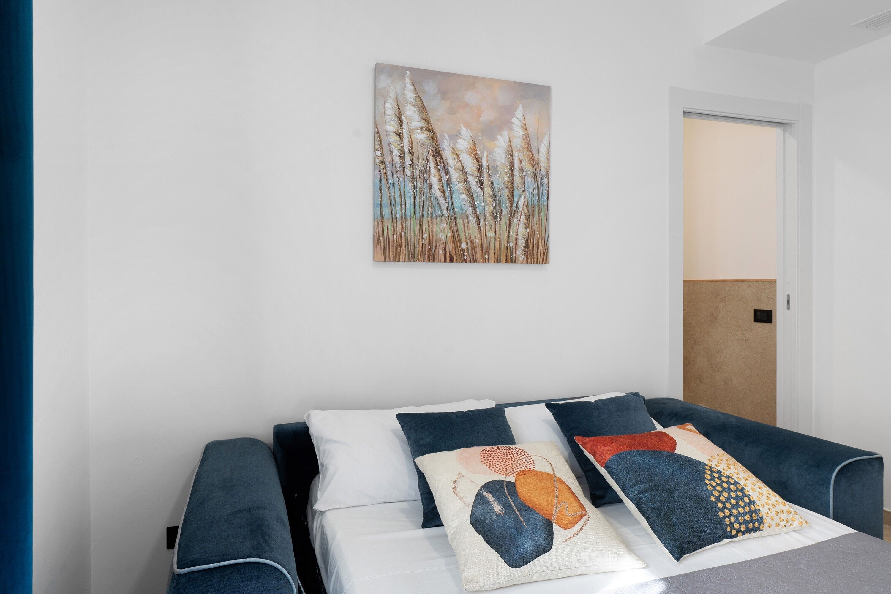 A modern bedroom with a bed, pillows, and a wall-mounted painting.