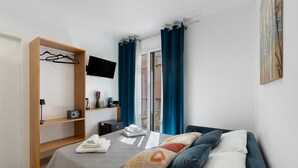 A bedroom with a bed, a wooden wardrobe, a flat-screen TV, and a view of the outside. - Room 'Camera 1 - P2' with Balcony, Wi-Fi and Air Conditioning (Balestrate)