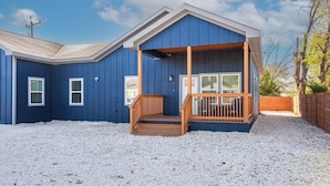 Ein blaues Haus mit einer Holzveranda und einer Auffahrt mit Kies.