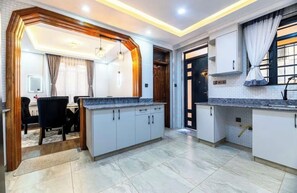 A modern kitchen with white cabinets, granite countertops, and a dining area with a black chair and table.