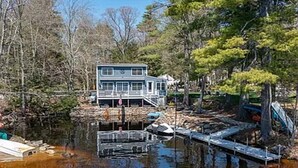 Una casa junto a un lago con un muelle y un embarcadero.