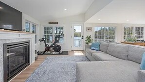 Un salón espacioso con chimenea, un sofá grande de color gris y una bicicleta estática.