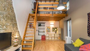 A loft-style living space with a wooden staircase, a TV, a sofa, and a lamp. - Apartment 'Le Case di Gilda' - Castiglione di Sicilia (Castiglione di Sicilia)