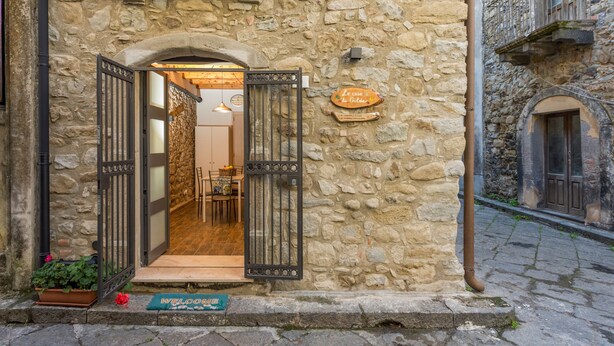 A stone building with an open entrance, a sign reading 'Le case de Gilda,' and a small table with chairs outside. - Apartment 'Le Case di Gilda' - Castiglione di Sicilia (Castiglione di Sicilia)