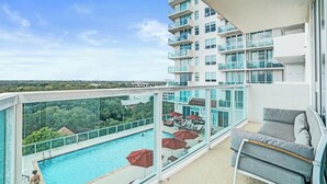 Ein moderner Hotelbalkon mit Pool, Glasgeländern und Sitzgelegenheiten im Freien.