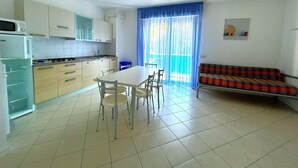 A compact living space with a kitchen, dining area, and a sofa. - COND. PELICAN - B2 5+1 - B80A4R (Bibione Pineda)
