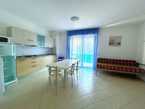 A compact living space with a kitchen, dining area, and a sofa. - COND. PELICAN - B2 5+1 - B80A4R (Bibione Pineda)