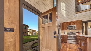 Une cuisine moderne avec des meubles en bois, des appareils électroménagers en acier inoxydable et un chemin de pierre menant à l’extérieur.