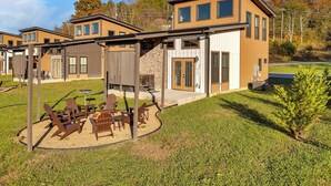 En moderne boligbygning med en patio med udendørs møbler og et bålsted.