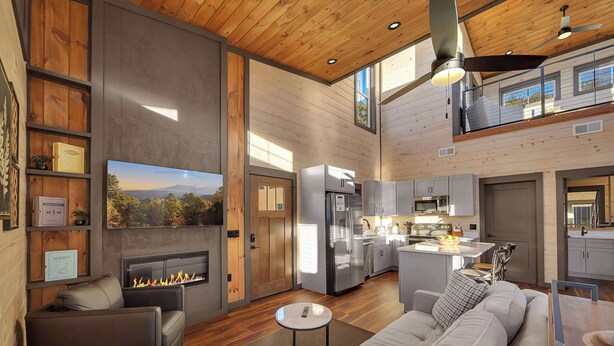 A spacious living room with a fireplace, a large sofa, and a television mounted on the wall. - Fab New 2 Level Build I Fire Pit I Private Hot Tub I Game Room (Sevierville)