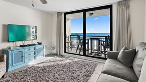 Ein Wohnzimmer mit großem Fenster, Deckenventilator, Flachbildfernseher und blauem Schrank.