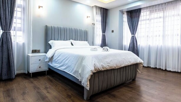 Un dormitorio moderno con una cama grande, suelo de madera y una mesita de noche.