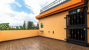 Una terraza en la azotea con suelo de madera, un portón negro y un lavamanos pequeño.