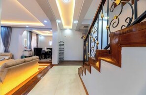 A modern interior with a sofa, a dining area, and a staircase with decorative railings.