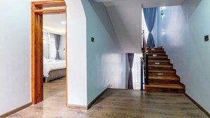 Un pasillo con una escalera de madera que conduce a un dormitorio.