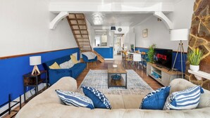 A spacious living room with a sofa, coffee table, and TV. A staircase leads to an upper level. - Heartwarming Windsor Cottage with Free Parking (Berkshire)