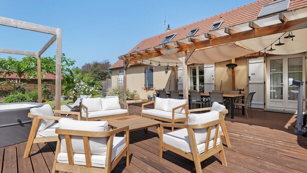 Une terrasse en bois avec des meubles d’extérieur, une pergola et un espace patio couvert.
