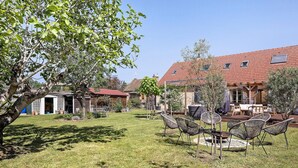 Il s’agit d’une propriété résidentielle dotée d’une pelouse bien entretenue, d’un espace extérieur aménagé pour se détendre et d’une maison avec un toit recouvert de tuiles rouges.