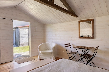 A room with a wooden ceiling, a white chair, a small table, and a mirror on the wall.. Chalet La Bienvenue in Vouzon with Wi-Fi