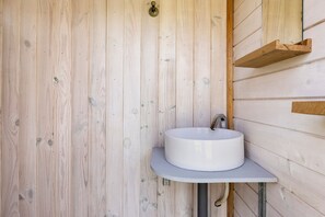 Pared de madera con un lavabo blanco y un grifo de metal.