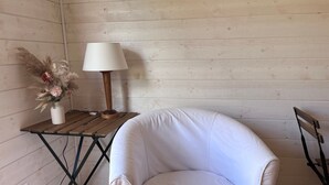 Un fauteuil en cuir blanc, une table en bois avec une lampe et un vase contenant des fleurs séchées.