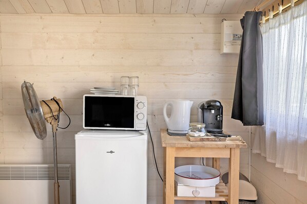 Cocina compacta con microondas, hervidor de agua, cafetera y ventilador.
