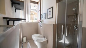 Un baño moderno con mampara de ducha de vidrio, un bidé y un inodoro.