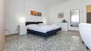 Une chambre à coucher avec un lit, des tables de chevet, un miroir et des œuvres d’art accrochées au mur.