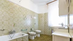 Une salle de bain avec une baignoire, deux toilettes et un lavabo.