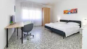 Une chambre d’hôtel avec un lit, un bureau, une chaise et un tableau au mur.