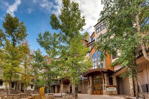 A multi-story hotel with stone pillars, a covered entrance, and a sign reading "HIGHLANDS SLOPESIDE." - Highlands Slopeside 502 (Beaver Creek)
