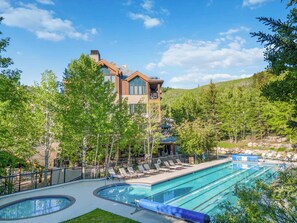 A modern building with a pool area, surrounded by trees and a hilly landscape. - Highlands Slopeside 502 (Beaver Creek)