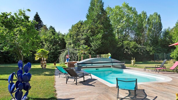 A swimming pool with a wooden deck, lounge chairs, and a decorative metal sculpture. - Guest Room 'Chambre Bleuet' with Breakfast Included (Lieurey)