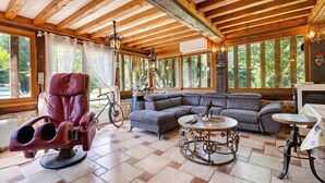 A spacious room with a wooden ceiling, a leather chair, a sofa, and a table with a clock. - Guest Room 'Chambre Bleuet' with Breakfast Included (Lieurey)