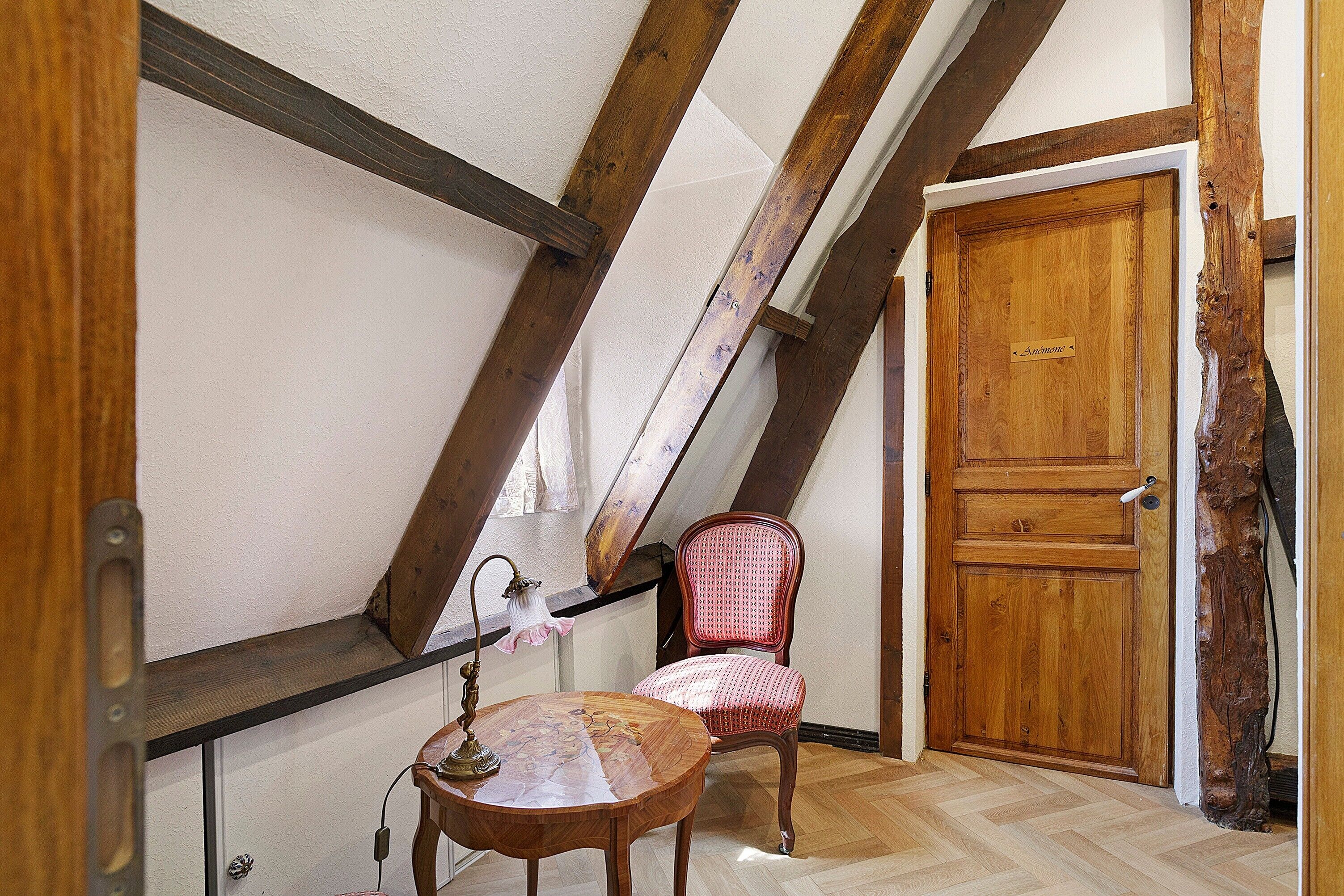 Une pièce avec une porte en bois, une chaise et une table sur laquelle se trouve une lampe.